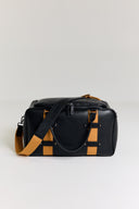 Black structured gym bag with mustard accents and shoulder strap draped over bag against white background