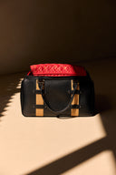 Black leather gym bag with a red interior on a beige surface