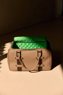 Beige leather gym bag with a green quilted interior on a beige surface